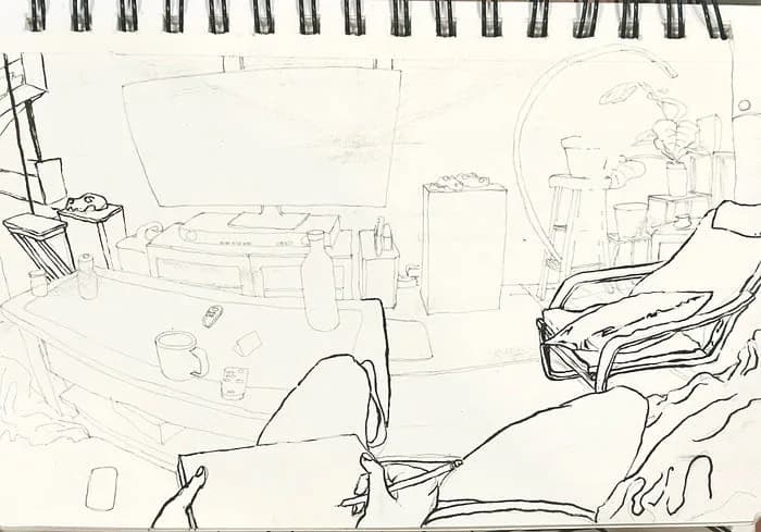 The living room drawing inked: bold black pen outlines over the pencil lines of the chair, couch and the artist's hands holding the sketchbook